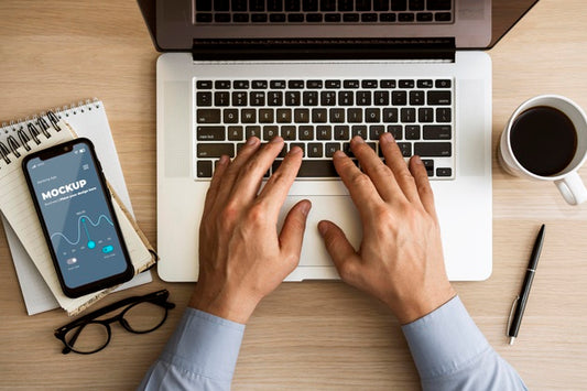 Free Top View Man Using Laptop Near Phone Mock-Up Psd