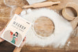 Free Woman Holding Book In The Kitchen With Flour And Sieve Psd