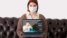 Free Woman With Masks Holding Laptop While Sitting On The Couch Psd