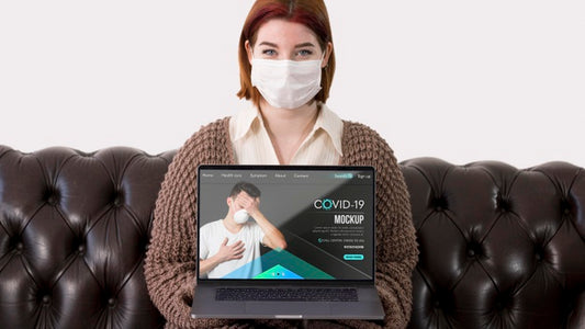 Free Woman With Masks Holding Laptop While Sitting On The Couch Psd